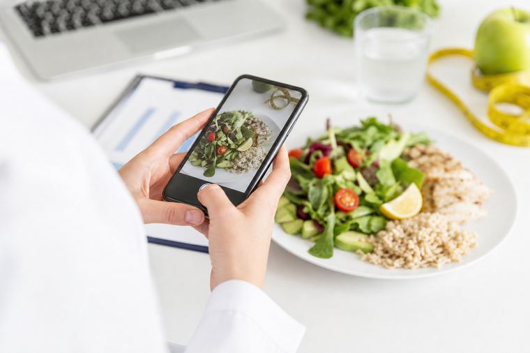 Avocado tagliato in una ciotola accanto a un telefono e a un barattolo di vetro.